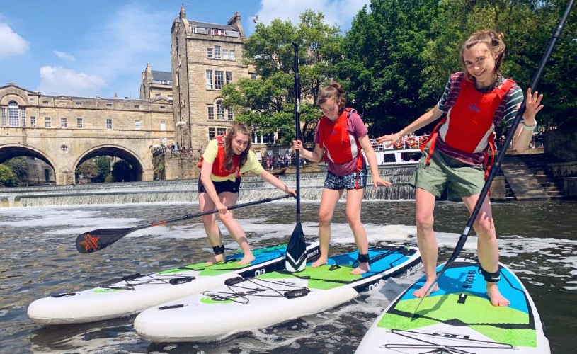 Three teenagers on paddleboards in Bath